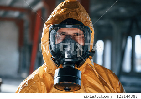 Portrait of man dressed in chemical protection suit that is in the ruins of the post apocalyptic building 125144385