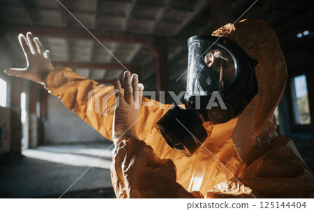 Light from nuclear explosion. Man dressed in chemical protection suit in the ruins of the post apocalyptic building Light from nuclear explosion. Man dressed in chemical protection suit in the ruins of the post apocalyptic building 125144404