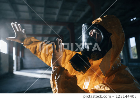 Light from nuclear explosion. Man dressed in chemical protection suit in the ruins of the post apocalyptic building Light from nuclear explosion. Man dressed in chemical protection suit in the ruins of the post apocalyptic building 125144405