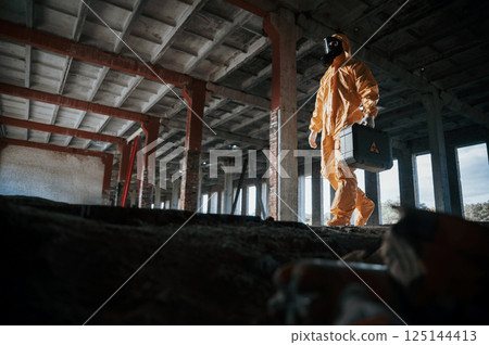 View from below. Man dressed in chemical protection suit in the ruins of the post apocalyptic building View from below. Man dressed in chemical protection suit in the ruins of the post apocalyptic building 125144413