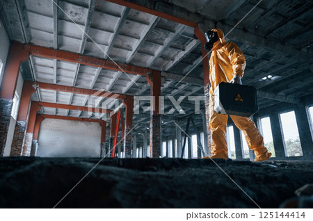 View from below. Man dressed in chemical protection suit in the ruins of the post apocalyptic building View from below. Man dressed in chemical protection suit in the ruins of the post apocalyptic building 125144414