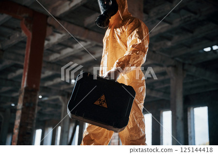 Bottom view. Man dressed in chemical protection suit in the ruins of the post apocalyptic building Bottom view. Man dressed in chemical protection suit in the ruins of the post apocalyptic building 125144418