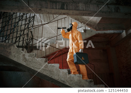 On the stairs. Man dressed in chemical protection suit in the ruins of the post apocalyptic building 125144450