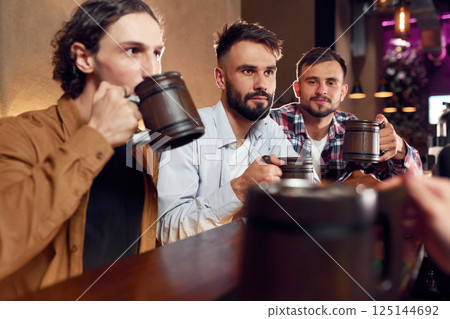 Three friends are in the bar drinking beer and having a good time 125144692