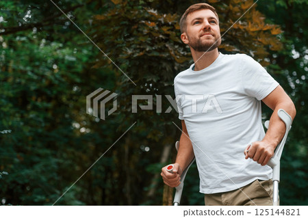 Enjoying the walk. Man with crutches is in the park outdoors. Having leg injury 125144821