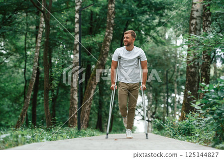 Enjoying the nature. Man with crutches is in the park outdoors. Having leg injury 125144827