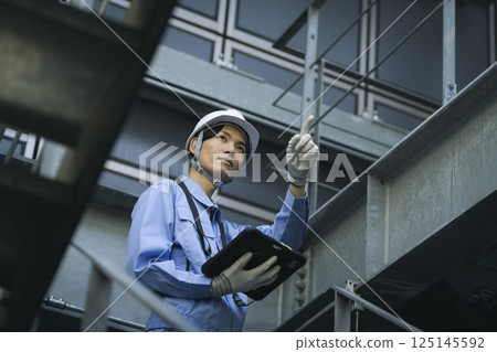 一個穿著工作服的男人帶著平板電腦 125145592