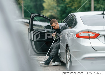 Injured man with crutches is going out from the car 125145633