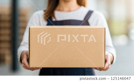 delivery and dropoff concept, Woman holding a cardboard box in a warehouse. 125146047