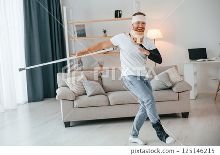 Dancing with crutches. Man is at home indoors. Having injuries 125146215