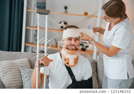 Taking care of bandage on the head. Woman is helping injured man at home 125146232