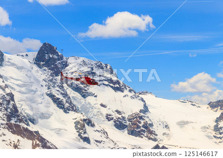 Helicopter flying over the snowy Swiss Alps in Switzerland Helicopter flying over the snowy Swiss Alps in Switzerland 125146617