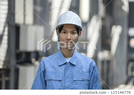 一名 30 多歲、身穿工作服的男子看著鏡頭 一名 30 多歲、身穿工作服的男子看著鏡頭 125146776