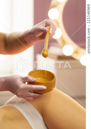 Therapist preparing honey mixture during beauty body treatment. 125146969