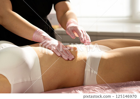 Therapist massages honey into abdomen during spa body session. Therapist massages honey into abdomen during spa body session. 125146970