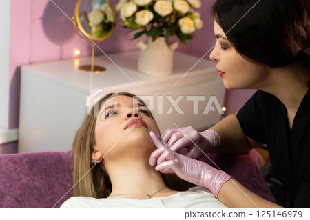 Specialist administers dermal chin filler in floral spa room Specialist administers dermal chin filler in floral spa room 125146979