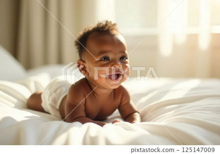 Smiling asian baby enjoying tummy time on soft bed in sunlit room with soft curtains in background. Baby products, baby care, newborn 125147009