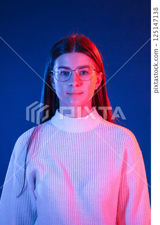Young beautiful woman is indoors in the studio illuminated by neon light 125147138
