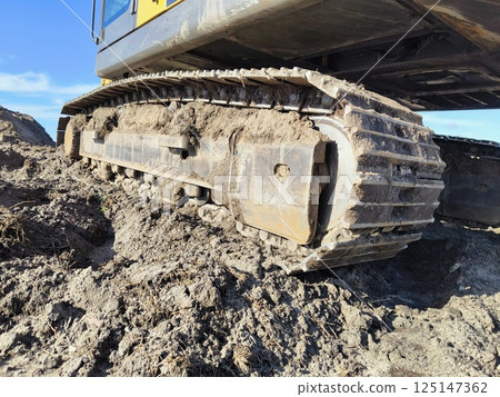 Caterpillars of a construction excavator in the sand at a construction site. close-up of a caterpillar of construction machinery in the sand Caterpillars of a construction excavator in the sand at a construction site. close-up of a caterpillar of construction machinery in the sand 125147362