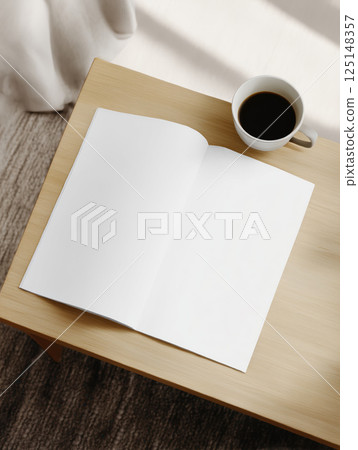 Open blank magazine and a cup of black coffee on a light wooden table. Soft daylight, minimalist setting. Ideal for mockups and lifestyle content. High quality photo 125148357