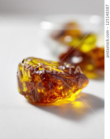 Ultra-realistic macro close-up of multiple natural amber stones with unique textures on white background under studio lighting. High quality photo Ultra-realistic macro close-up of multiple natural amber stones with unique textures on white background under studio lighting. High quality photo 125148387
