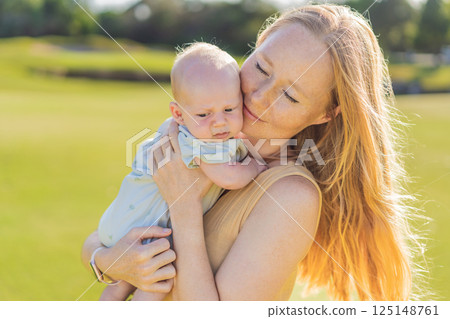Mother and newborn baby on a meadow in the park. Tender bonding moment in nature. Parenthood, love, and family connection concept 125148761