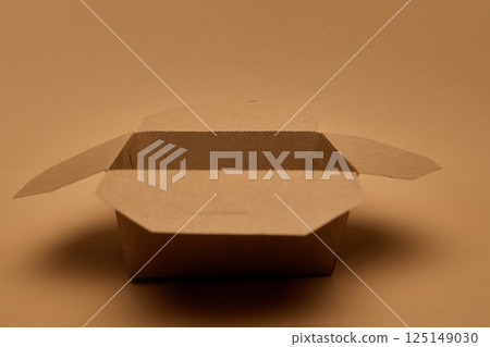 Open empty brown cardboard container on brown surface, eco packaging. Concept of zero waste, food delivery, storage solution. Open empty brown cardboard container on brown surface, eco packaging. Concept of zero waste, food delivery, storage solution. 125149030