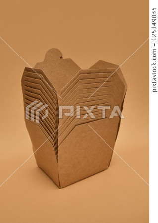 Stacked kraft paper food boxes against light brown background. Concept of packaging, delivery, recycling, eco materials. 125149035