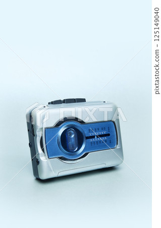 Silver and blue personal cassette player against light blue background. Portable retro audio technology. 125149040