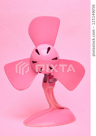 Monochromatic bright pink electric fan against textured light pink background. Cooling and vibrant aesthetic. Air conditioning, fan products. 125149056
