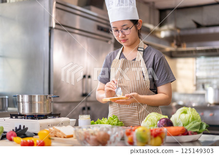 Young Female Chef Preparing Food in a Professional Kitchen 125149303