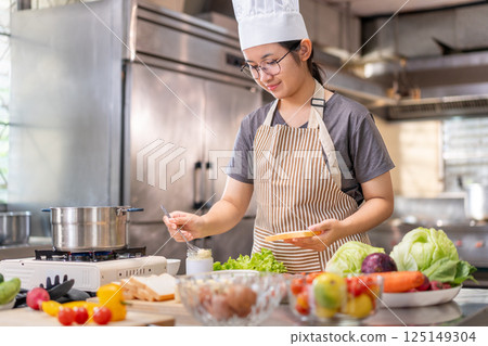 Young Female Chef Preparing Food in a Professional Kitchen 125149304