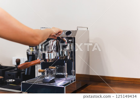 Barista hand presses a button while making fresh coffee. 125149434