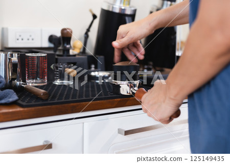 Barista leveling ground coffee in the portafilter. Barista leveling ground coffee in the portafilter. 125149435