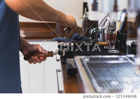Barista hands leveling coffee in portafilter using powder distribution. Barista hands leveling coffee in portafilter using powder distribution. 125149436