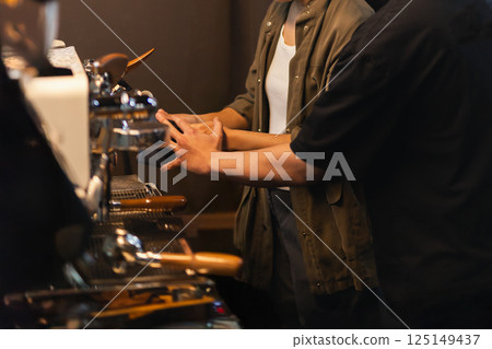 Barista coaching teaching woman to brew coffee in cafe. Barista coaching teaching woman to brew coffee in cafe. 125149437