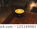 Hot latte coffee cup on wooden tray with heart latte art on wood table. 125149983