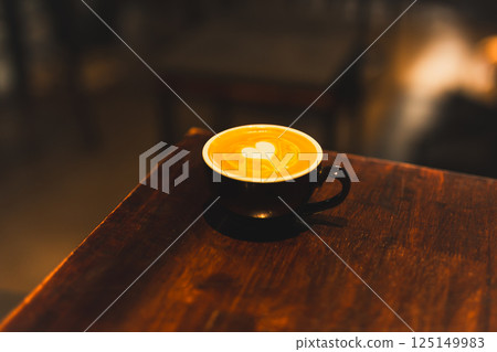 Hot latte coffee cup on wooden tray with heart latte art on wood table. 125149983