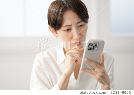 一個臉色難看的女人看著她的智能手機 一個臉色難看的女人看著她的智能手機 125149996