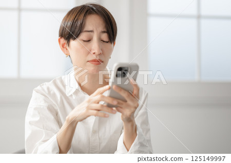 A woman with a troubled face looking at her smartphone A woman with a troubled face looking at her smartphone 125149997