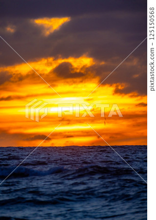 A Stunning Sunset Over the Serene and Peaceful Ocean Waves Creates a Breathtaking View A Stunning Sunset Over the Serene and Peaceful Ocean Waves Creates a Breathtaking View 125150568