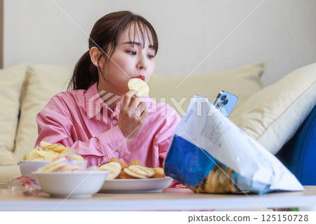 一個女人一邊吃著糖果一邊看著她的智能手機 125150728