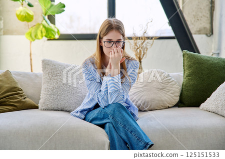 Sad stressed young woman sitting at home on the couch 125151533