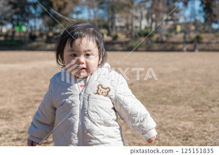 [A one-year-old child playing on the grass at Sagamihara Municipal Asamizo Park] 125151835