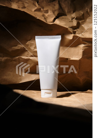 Place for text. A white bottle of cosmetics on a brown textured background. Rocks and sand. 125152022