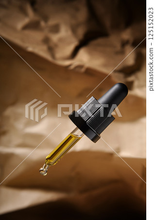 Close-up of essential jujube oil or serum in a pipette isolated on a brown background. Paper. Rocks. Cosmetic pipette.  125152023