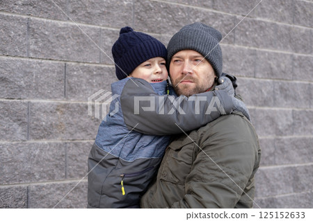 Father and son walking down on sidewalk together. Portrait of a handsome middle-aged man with toddler boy in the urban street. Dad and his child sitting on a bench in city park. City life. Family Father and son walking down on sidewalk together. Portrait of a handsome middle-aged man with toddler boy in the urban street. Dad and his child sitting on a bench in city park. City life. Family 125152633