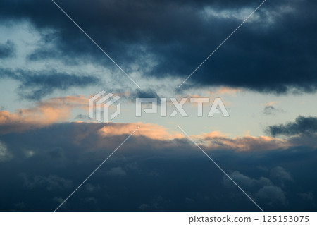 Blue sky during the day. The weather is bad. Fluffy clouds. Light breaks through the clouds. Universal horizontal photo. The background picture.  125153075