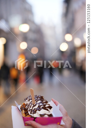 Person Holding Belgian Waffle with Cream and Chocolate in City Street Person Holding Belgian Waffle with Cream and Chocolate in City Street 125153160