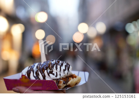 Hand Holding Belgian Waffle with Cream and Chocolate Hand Holding Belgian Waffle with Cream and Chocolate 125153161